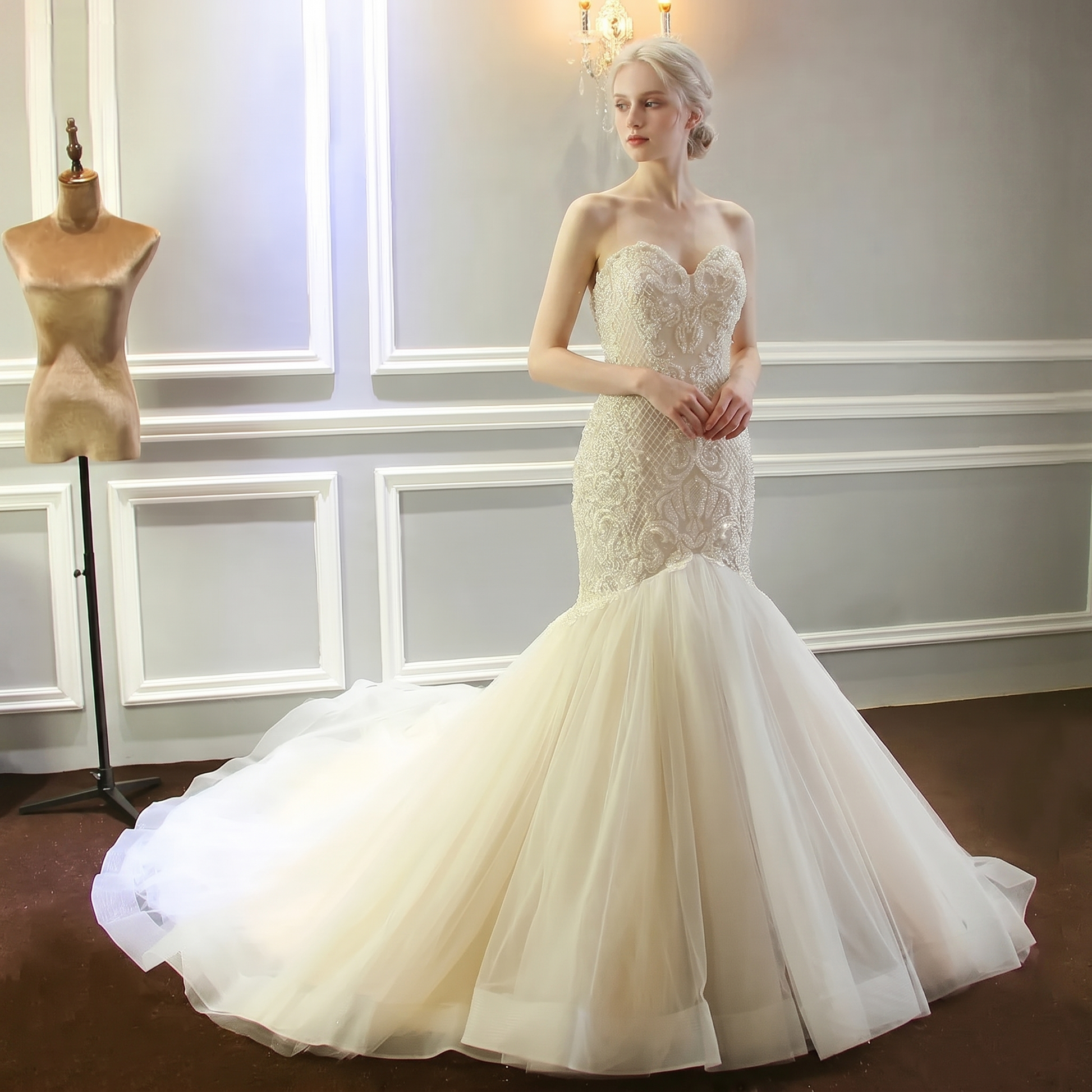 Front view of an elegant champagne mermaid wedding dress on a model, featuring a fully beaded shiny bodice, sweetheart neckline, and a dramatic flared tulle skirt.