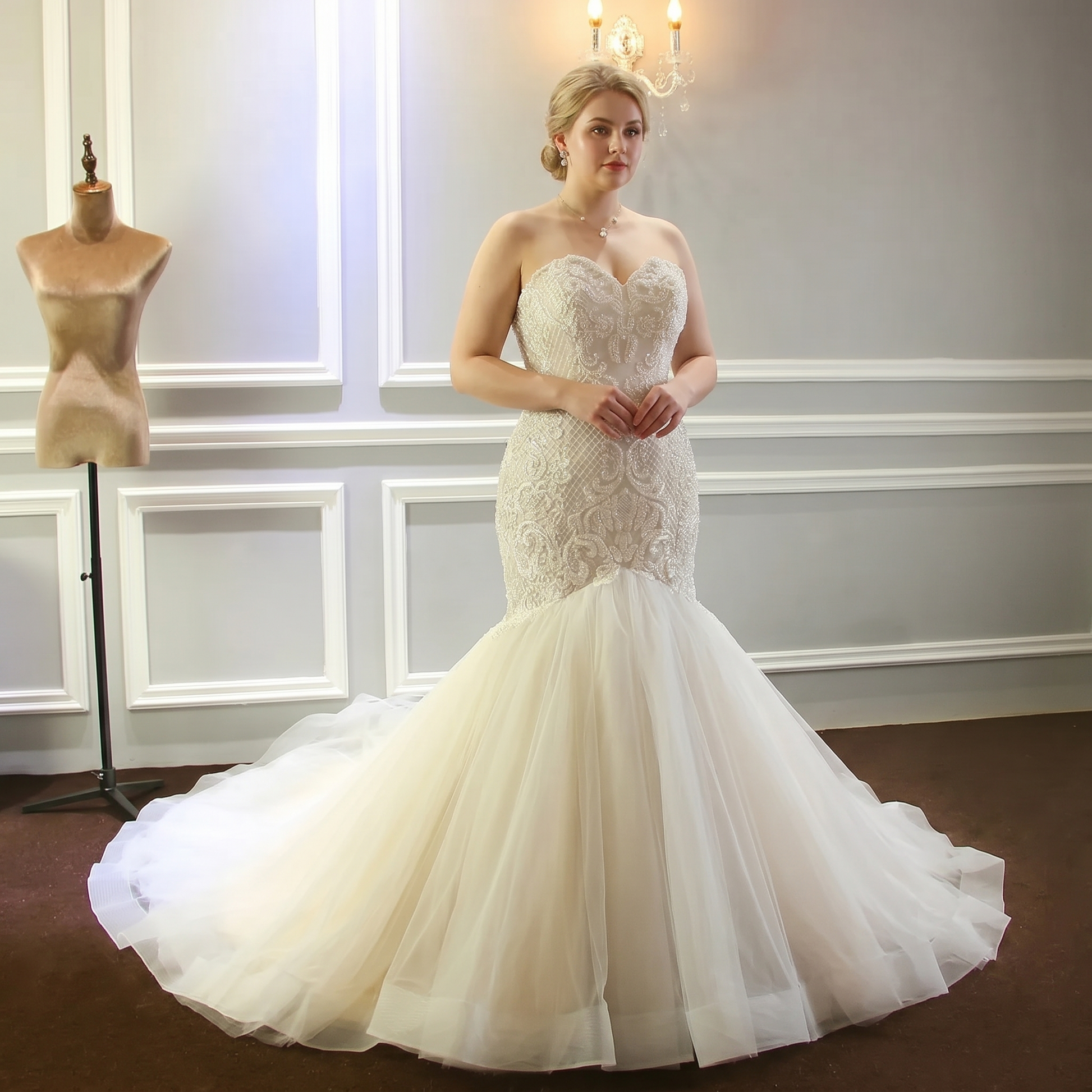 A plus-size model showcasing the luxury champagne beaded mermaid bridal gown with shimmering embroidery and a voluminous fit-and-flare silhouette.