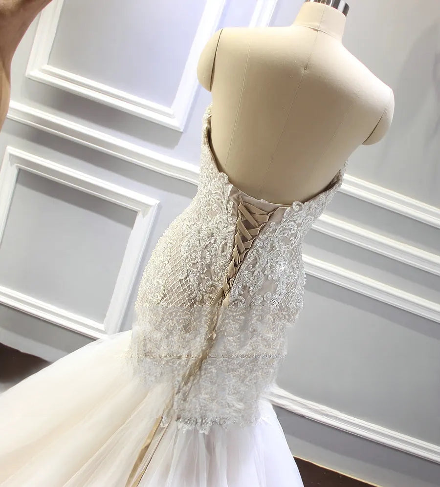 Close-up detail of the luxury bridal gown’s bodice on a mannequin, focusing on the heavy champagne beadwork, pearl accents, and sparkling sequin embroidery.