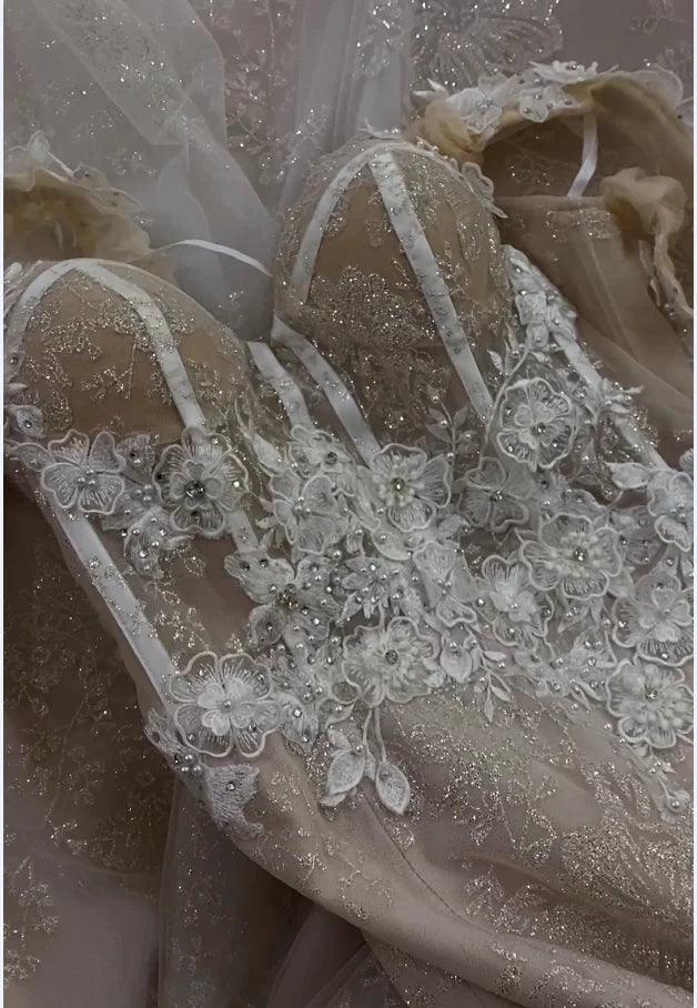 Close-up detail of the 3D floral lace appliqués and premium beadwork on the bodice of a champagne mermaid wedding gown.