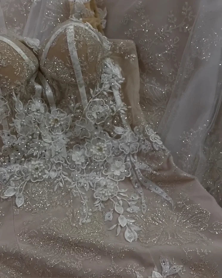 Detailed view of the shimmering champagne fabric and luxury floral embroidery on the skirt of a mermaid style wedding dress.