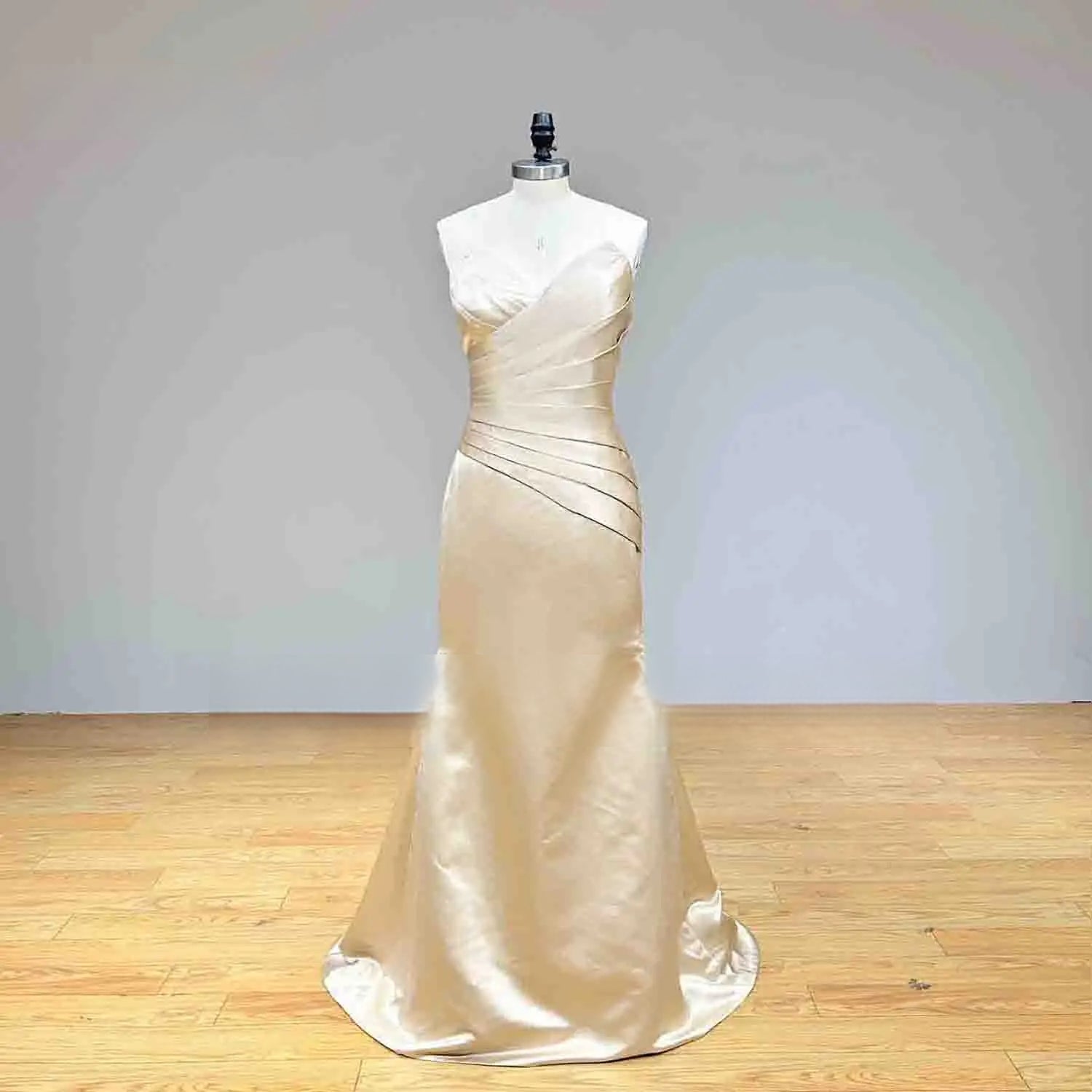 Front view of the champagne satin mermaid wedding dress without the train, showing the sophisticated fit-and-flare silhouette and side-pleated details.
