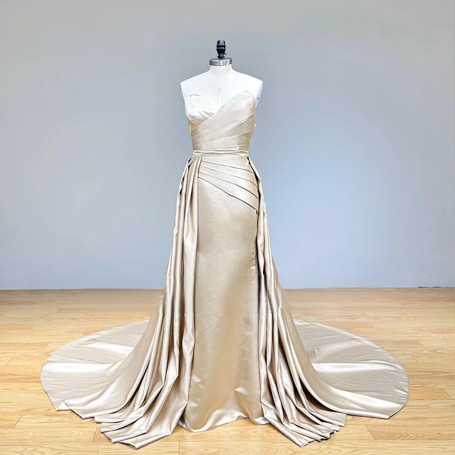 Full-length studio display of a luxury champagne satin 2-piece wedding dress set including a fitted mermaid gown and a voluminous detachable train extension.