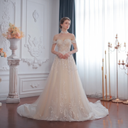 Full-length front view of a charming A-line off-shoulder wedding dress with a champagne undertone and intricate white lace appliqués.