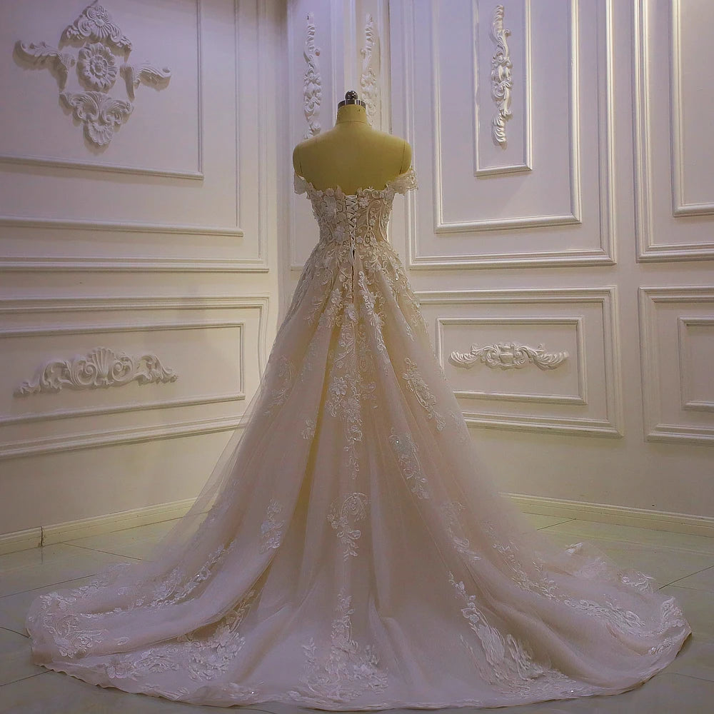 Rear view of an ivory lace wedding dress highlighting a traditional lace-up corset back and trailing floral embroidery on the train.