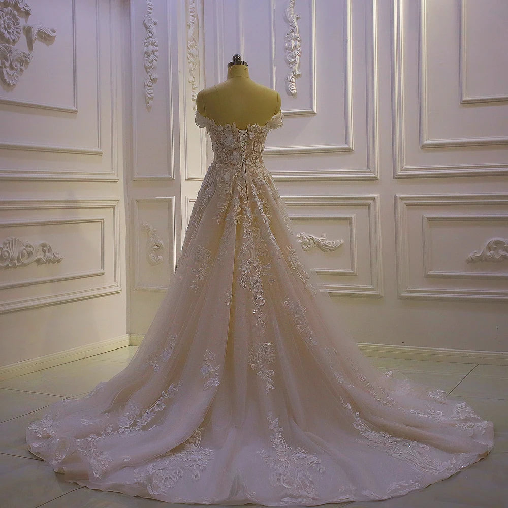 Full back profile of a romantic off-shoulder bridal gown emphasizing the structured corset bodice and expansive lace-trimmed A-line skirt.
