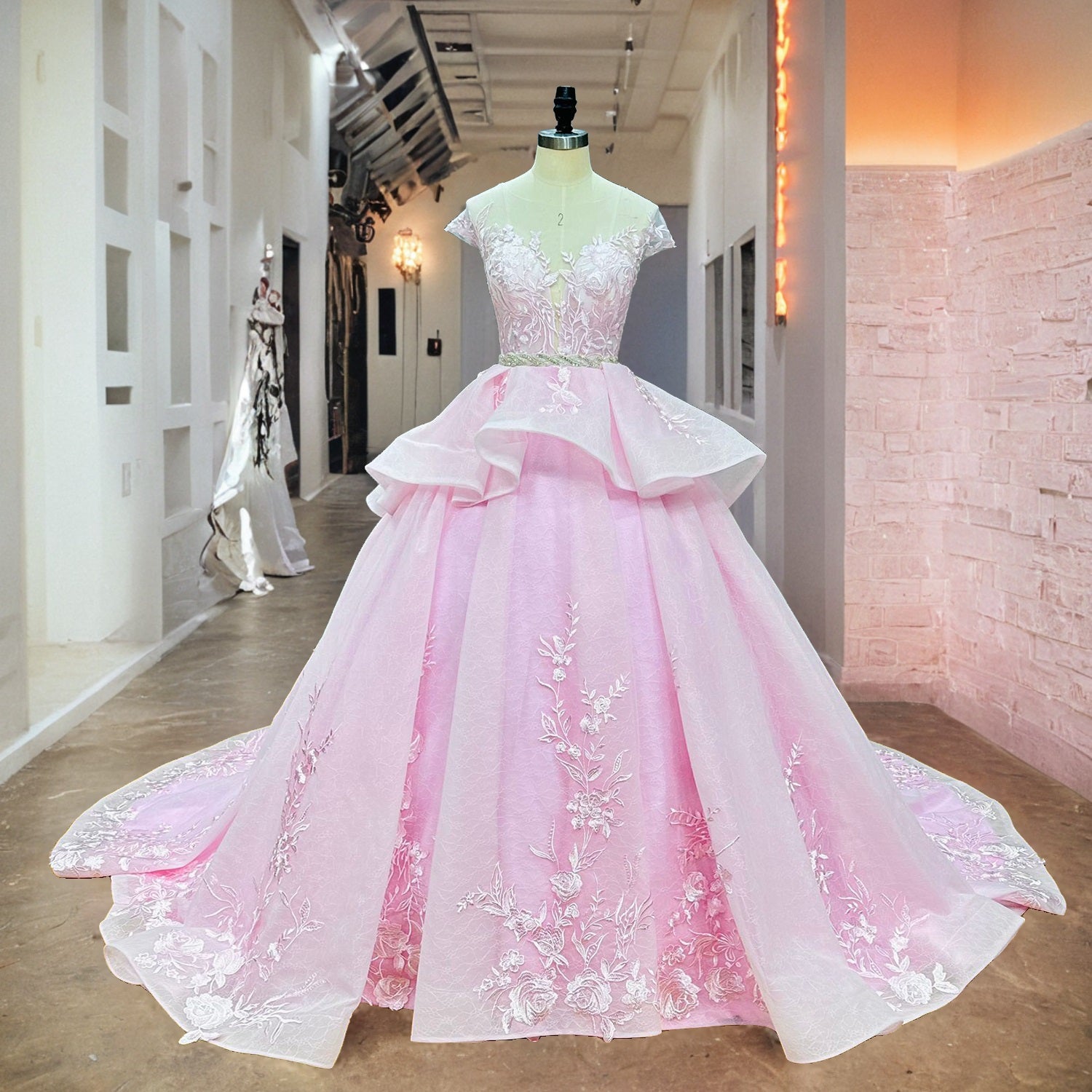 Front view of the pink and white ball gown bridal dress featuring a crystal beaded belt and unique peplum tiers displayed on a mannequin in a boutique showroom.