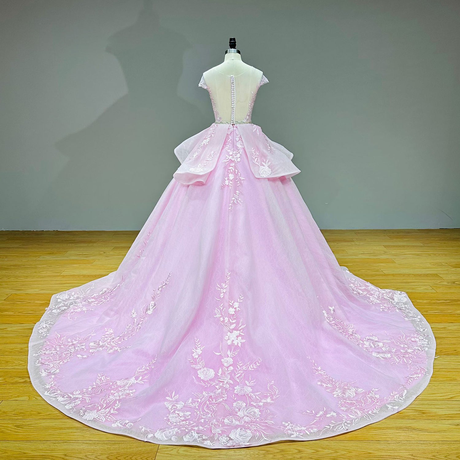 Full-length studio back view of the pink ball gown wedding dress on a mannequin, showcasing the illusion back, covered buttons, and an embroidered cathedral-length train.