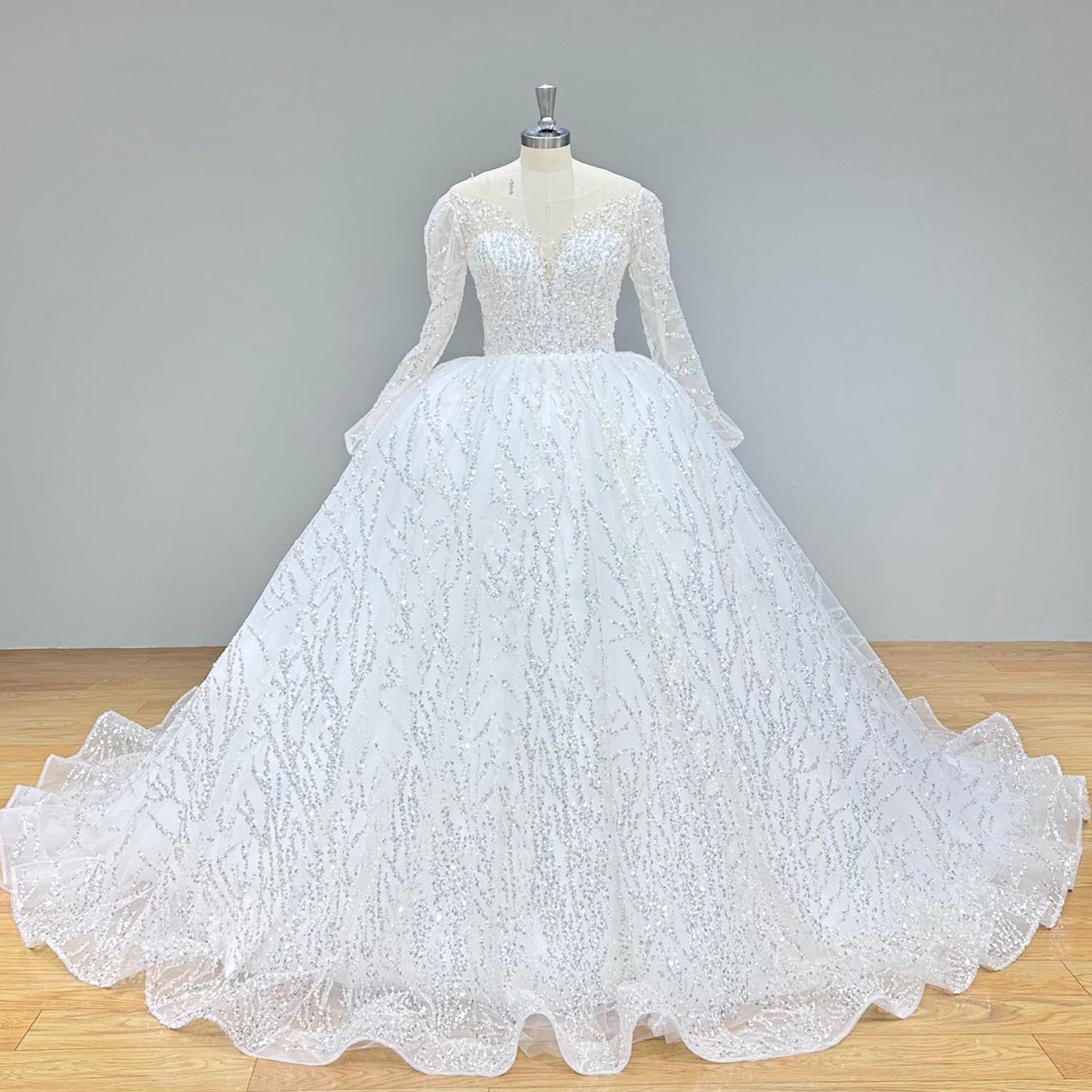 Back view of a backless long sleeve lace wedding dress featuring elegant button closures and illusion lace detailing on a mannequin.