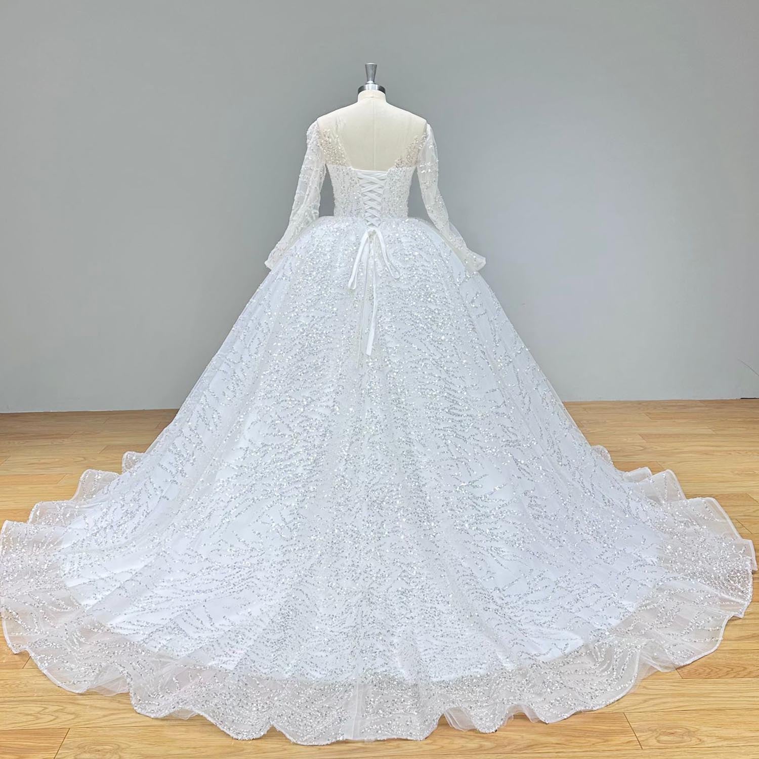 Angled back view of a classic long sleeve backless lace wedding dress, highlighting the beaded textures and elegant fit.