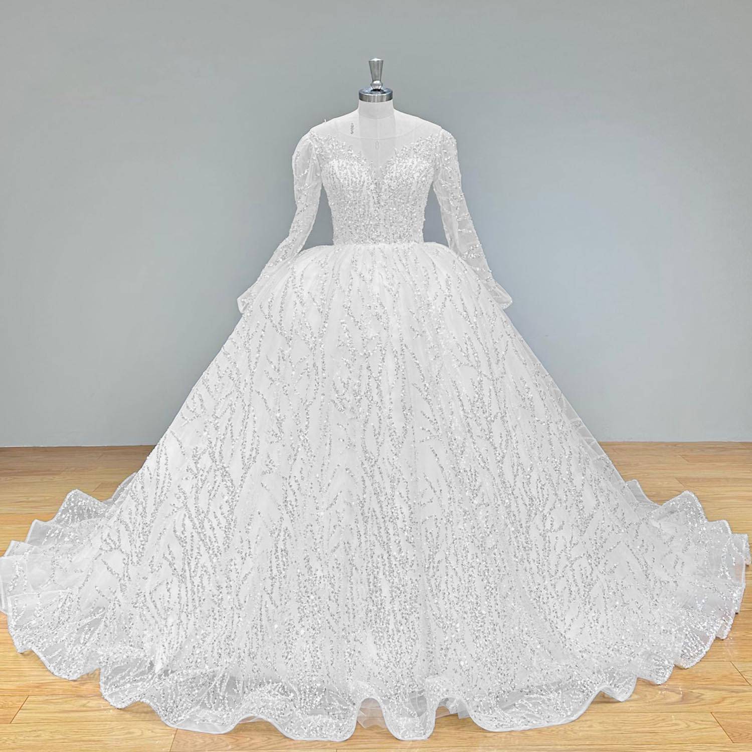 Back view of an elegant backless lace bridal gown with long sleeves and an intricate, sweeping train on a display mannequin.