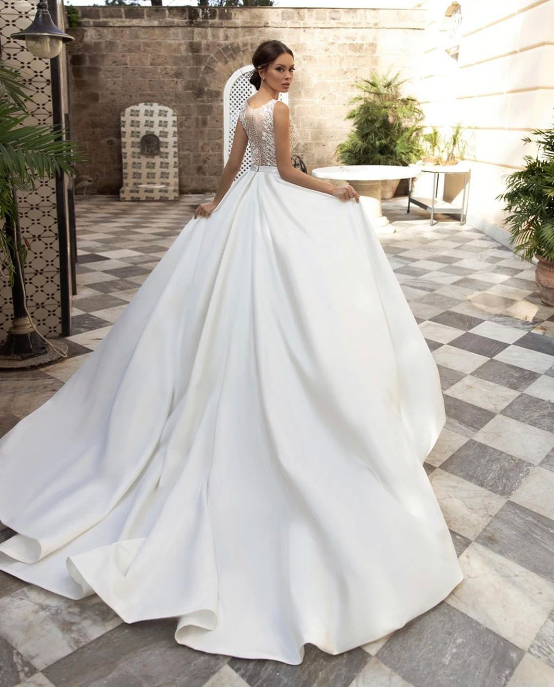 Rear full-length view of an A-line satin wedding dress with a long train, highlighting the detailed lace bodice and graceful silhouette.