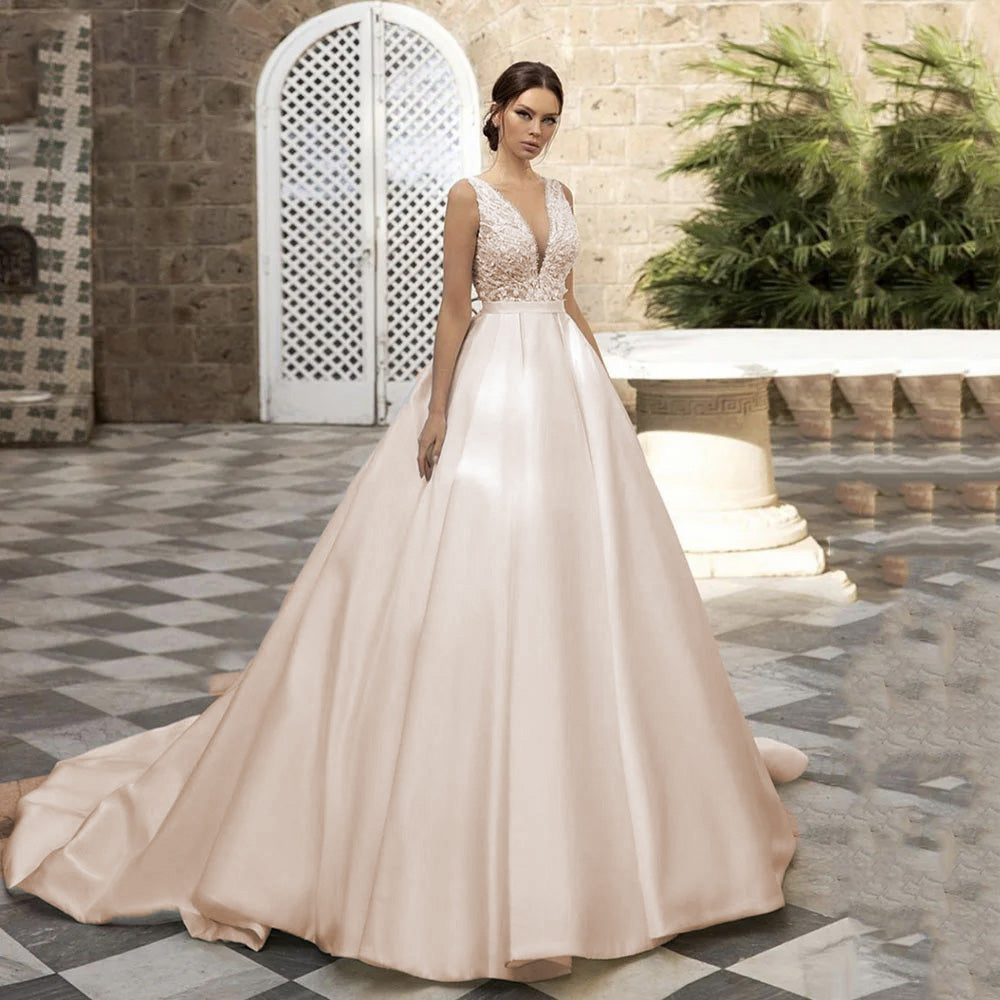 A bride wearing a timeless A-line satin wedding dress with a V-neck and lace embroidery, captured in an outdoor setting.