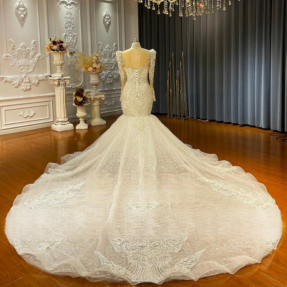 Rear view of the luxury crystal-embellished mermaid wedding dress on a mannequin, highlighting the open-back design, corset lacing, and expansive shimmering train.