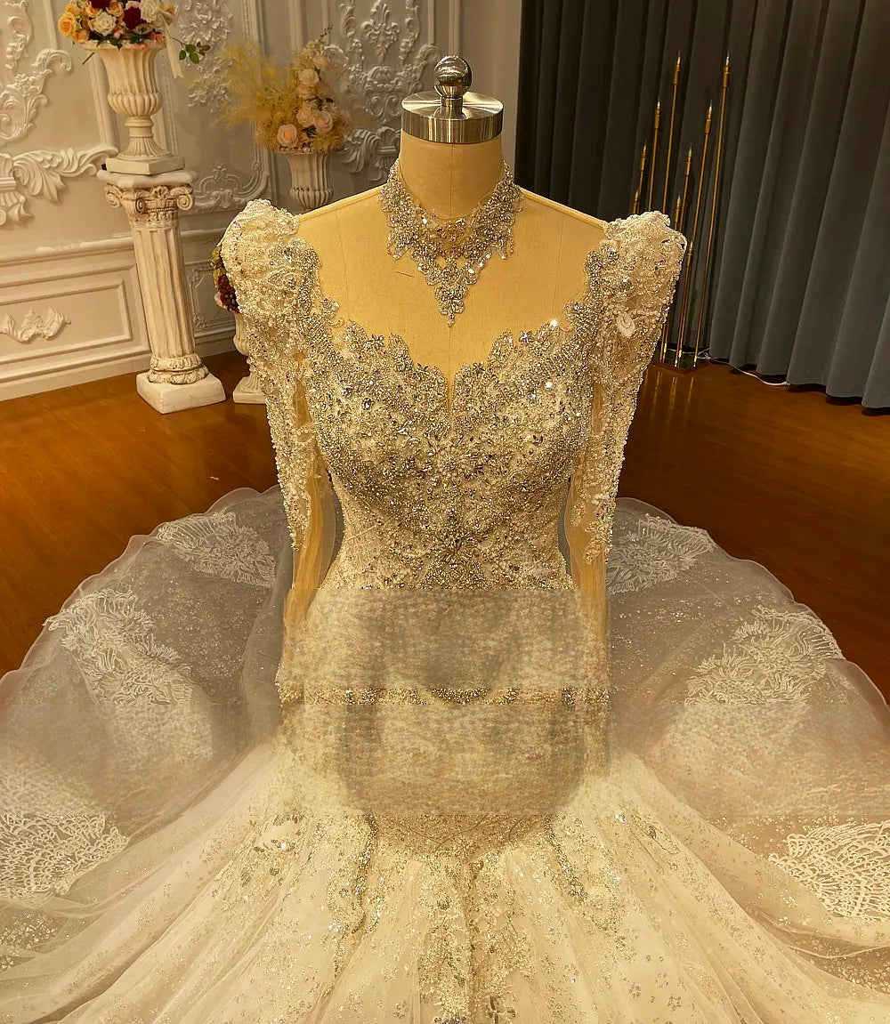 Close-up detail of the bodice on a luxury mermaid wedding dress, emphasizing the heavy crystal embellishments, sweetheart illusion neckline, and matching high collar.