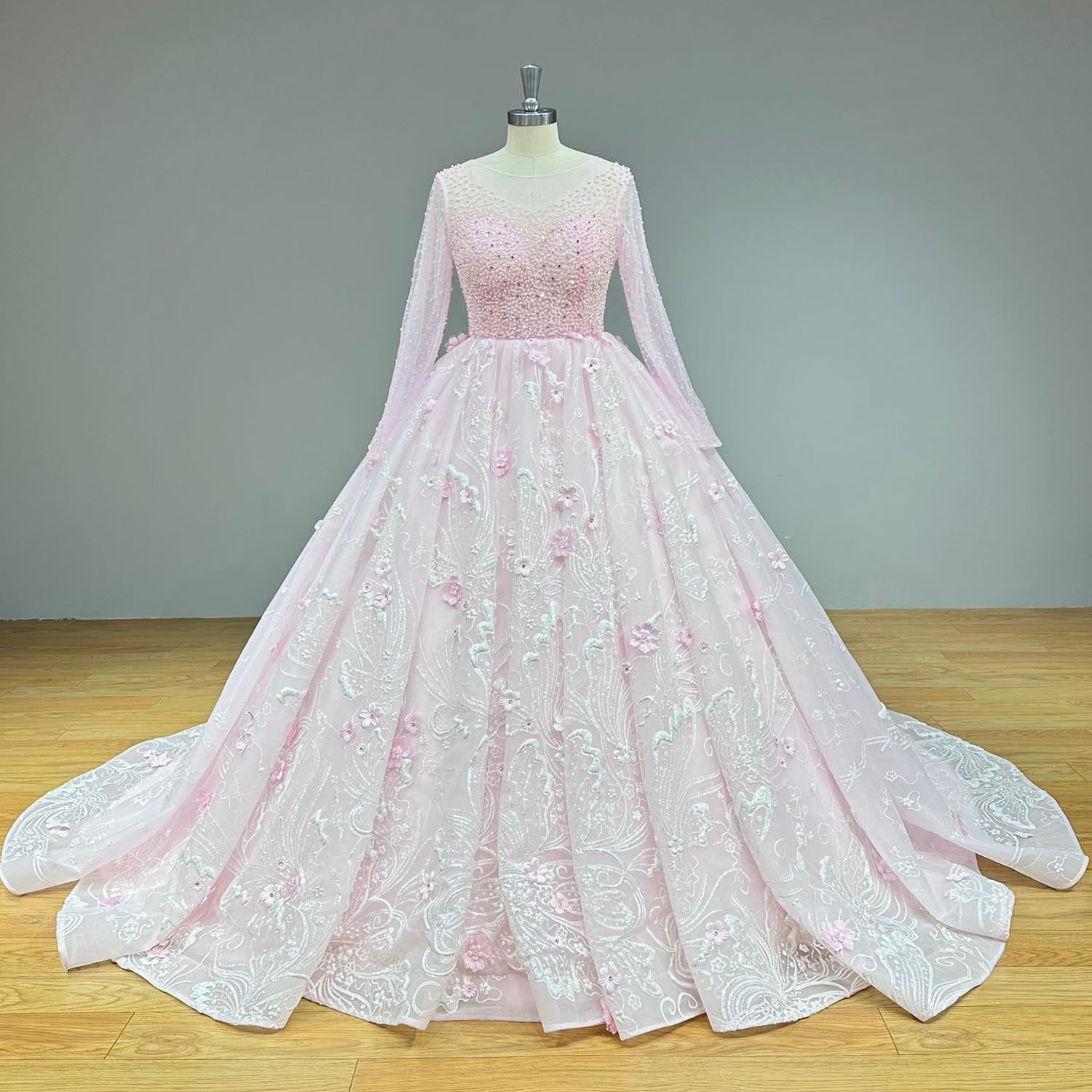 Front view of an a-line blush pink colored Muslim wedding gown on a dress form, displaying an ornate rhinestone-encrusted bodice and a sweeping scalloped train