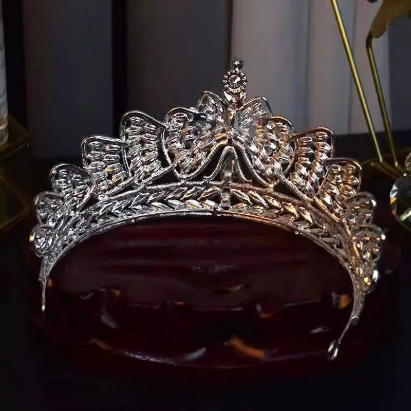 A premium crystal bowknot bridal crown tiara resting upside down on a dark wooden base, showcasing its inner silver framework.