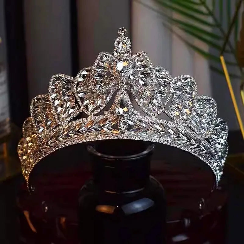 A luxury silver rhinestone wedding headpiece styled as a bowknot tiara crown, beautifully placed over a black glass display bottle.