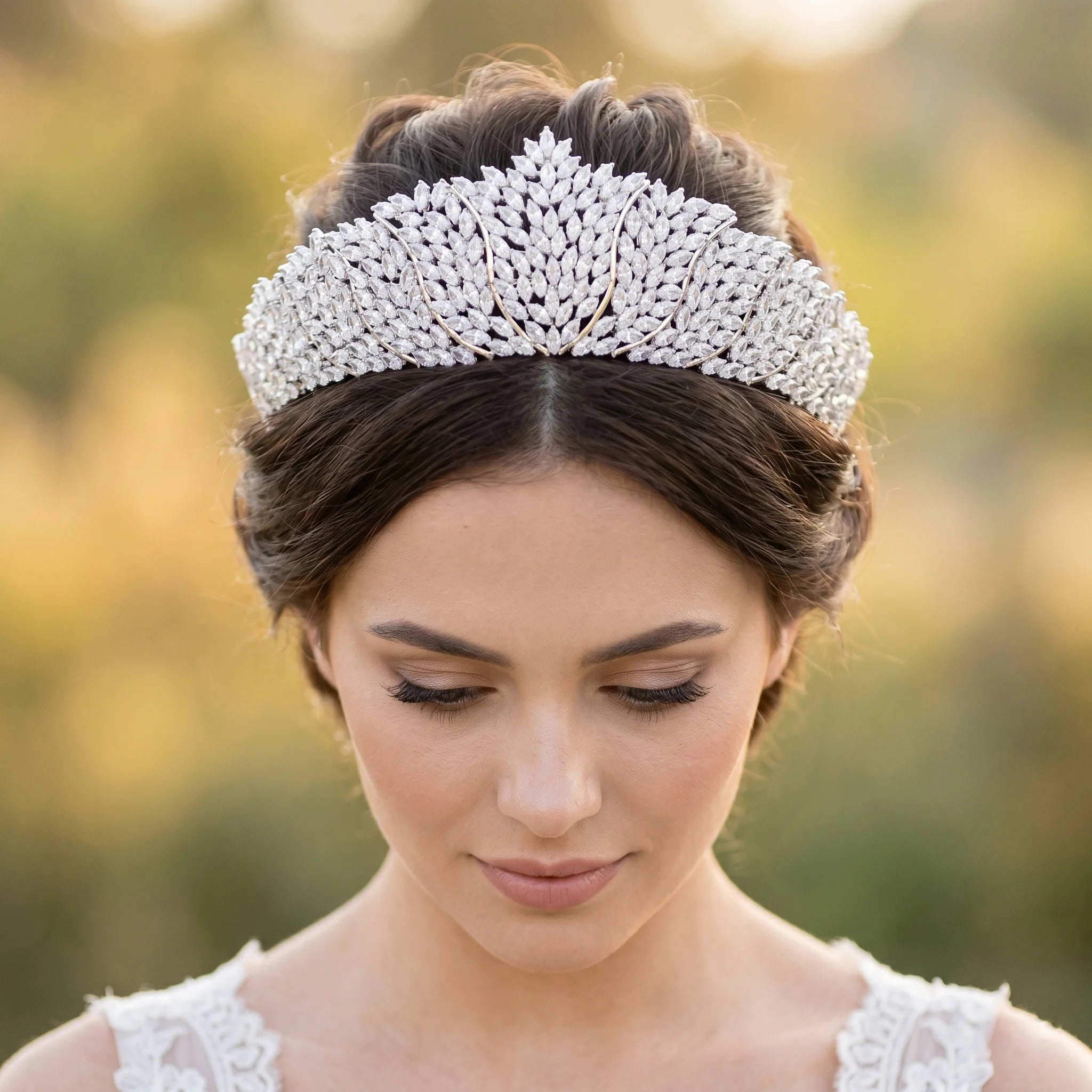 Close-up of a model wearing a luxury crystal bridal tiara crown with a layered marquise rhinestone leaf pattern.