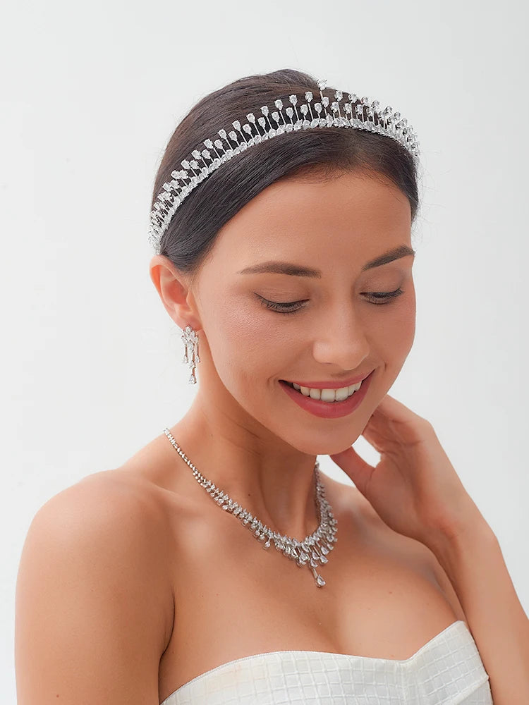 Smiling model wearing a sleek crystal bridal tiara headband with a matching wedding necklace and earrings.