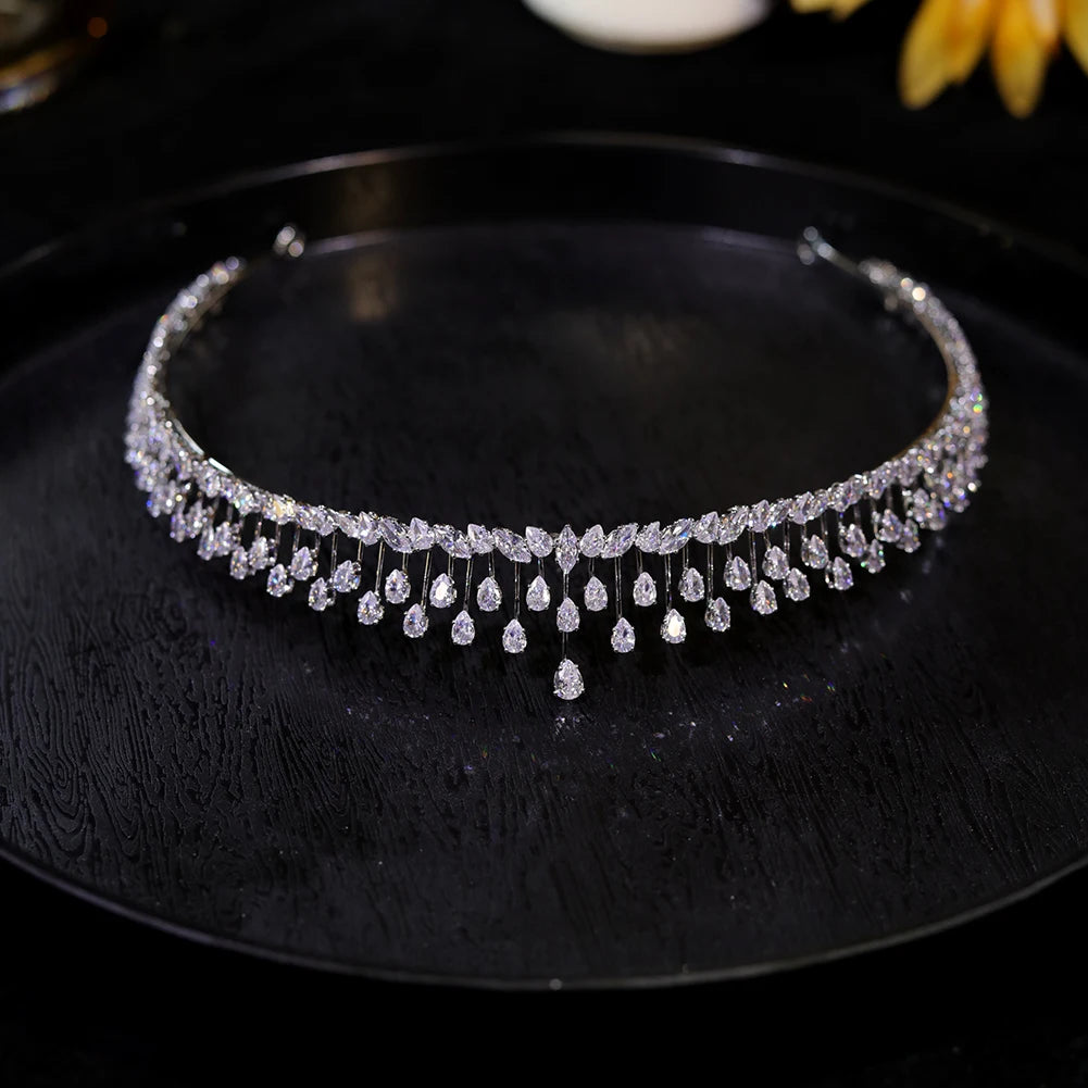 Flat lay angle of a sparkling rhinestone bridal crown for women placed on a dark reflective surface.