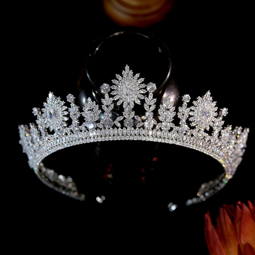 Front view of a sparkling crystal wedding tiara crown with intricate snowflake and floral diamond patterns on a dark background.