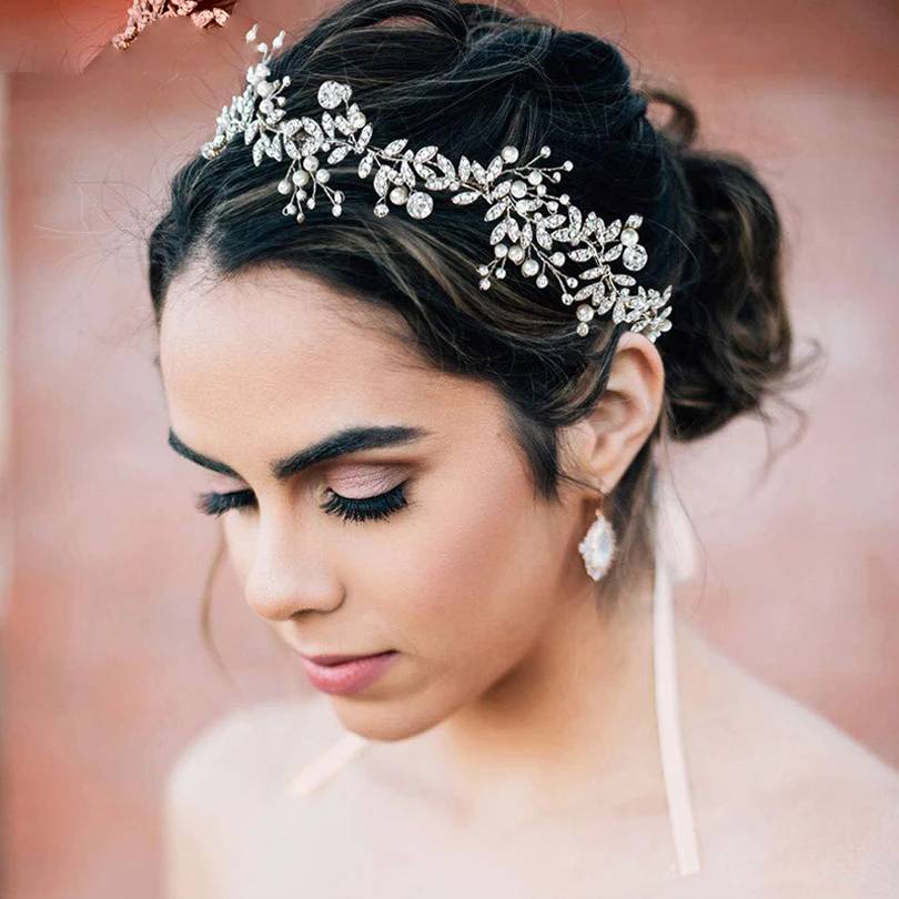 A bride wearing an elegant silver crystal flower and pearl bridal headband as a wedding hair accessory.