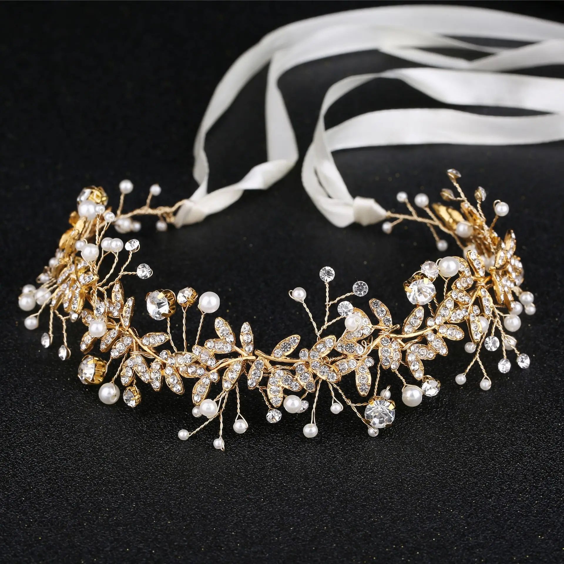 A luxurious gold crystal and pearl floral wedding headband with tied ribbon bows.