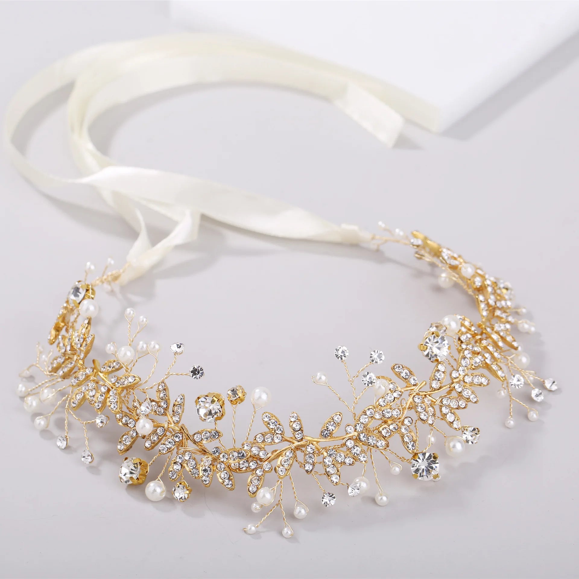 Close-up of a gold floral bridal headband with crystal embellishments and pearl accents.
