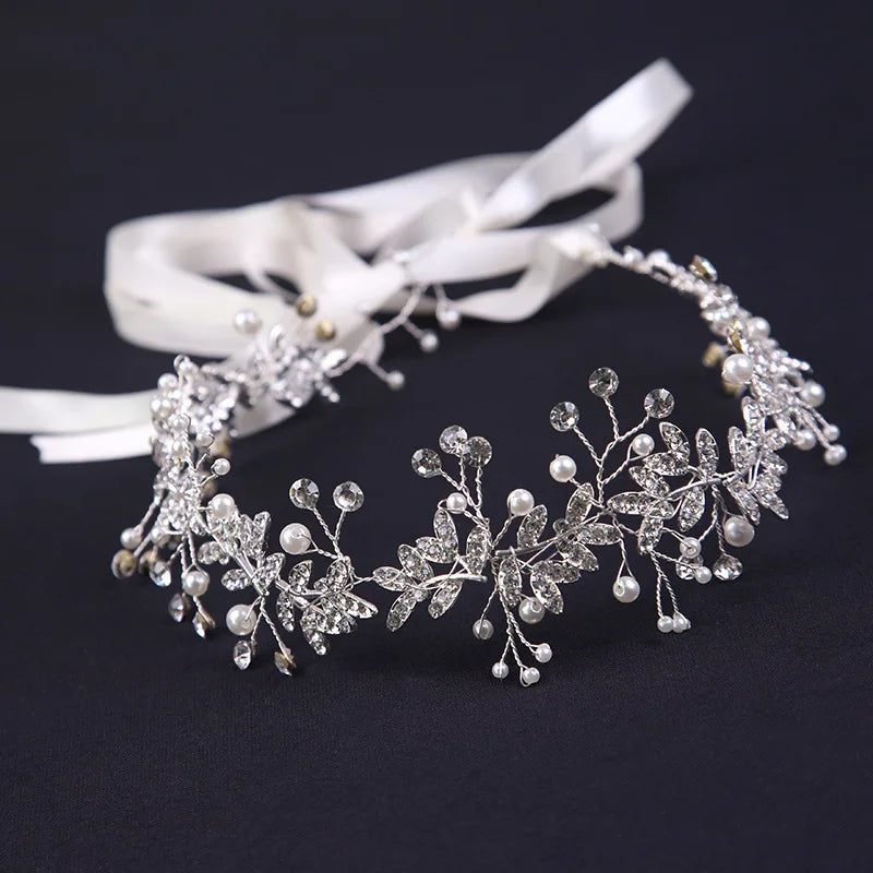 Detailed side view of a silver crystal and pearl bridal hair piece with tied ribbon.