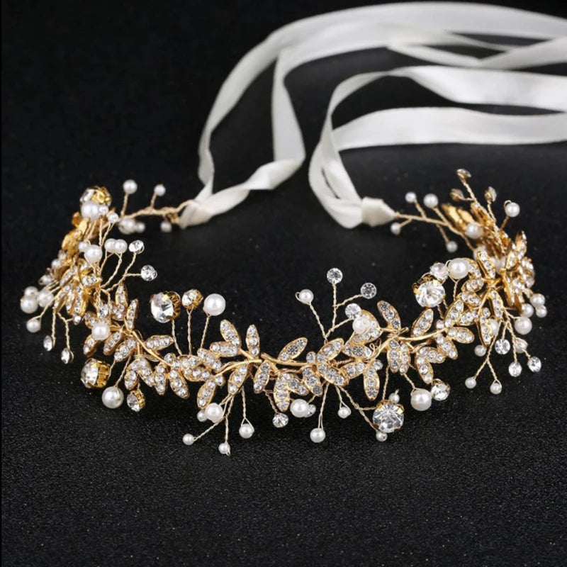 A close-up shot of an ornate gold crystal and pearl wedding hairband with ribbon ties.