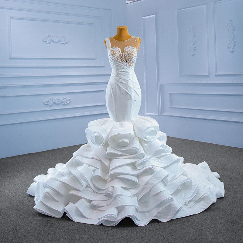 Showroom display of a white mermaid wedding dress on a mannequin, highlighting the contrast between the fitted pearl lace bodice and the grand ruffled satin bottom.