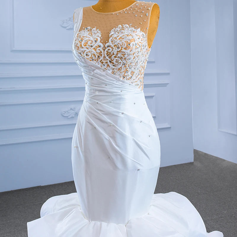 Close-up detail of a luxury wedding dress bodice showing asymmetrical satin draping accented with scattered crystals and fine pearl beadwork.