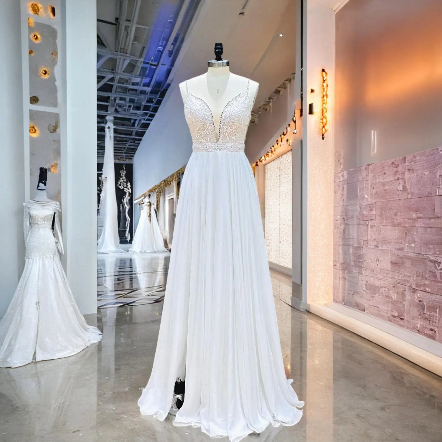 Mannequin display of a beautiful white chiffon wedding dress with a deep V-neck lace bodice, delicate crystal straps, and an elegant side slit.