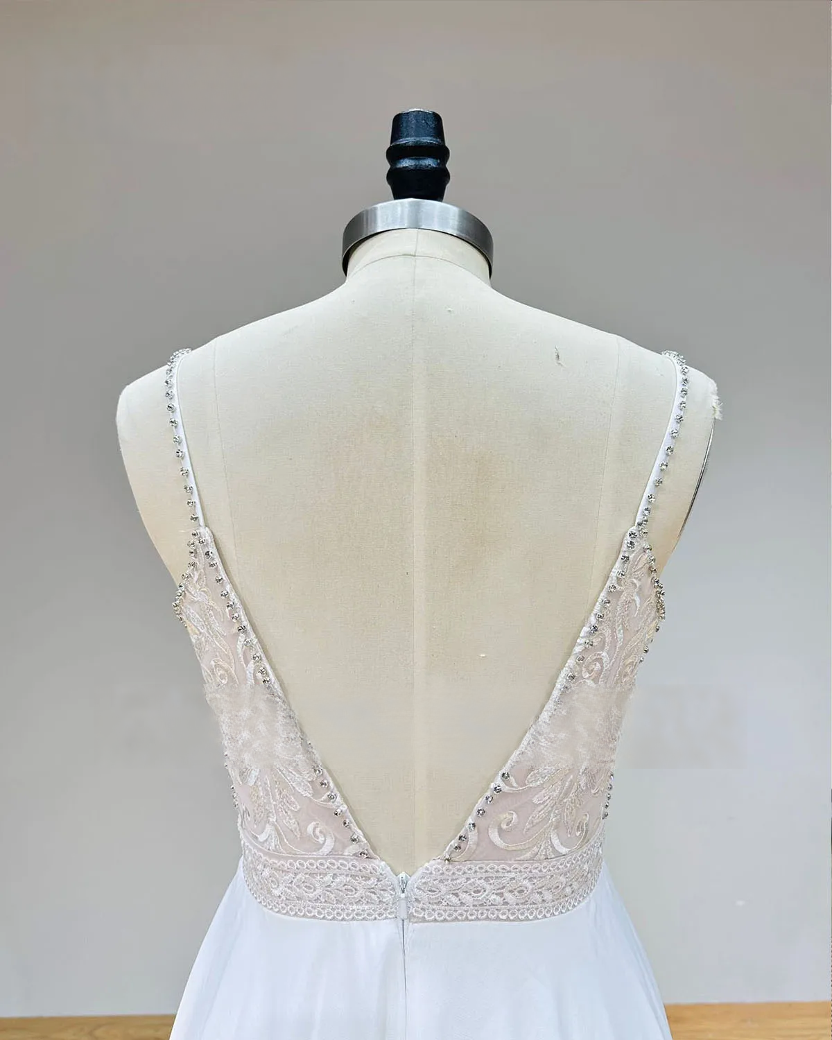 Detailed view of the open V-back design on a backless chiffon wedding dress, highlighting the sheer lace panels and crystal beaded straps.