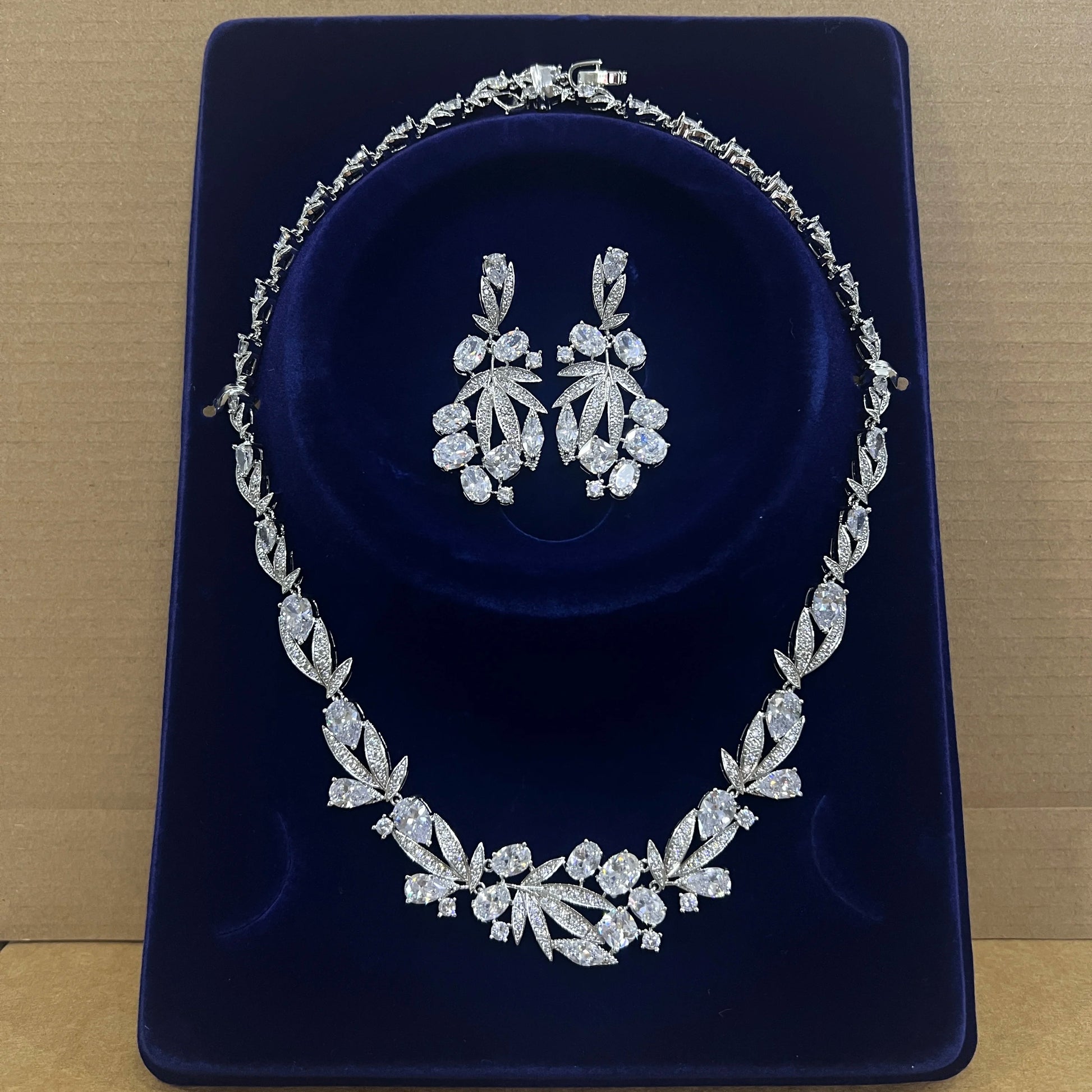 Premium cubic zirconia bridal choker necklace and matching statement earrings presented inside a luxury blue velvet display box.