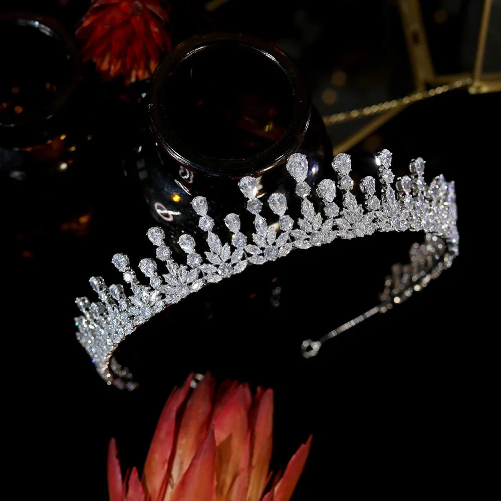 High-end silver cubic zirconia bridal crown displayed on a reflective black surface alongside luxury accents