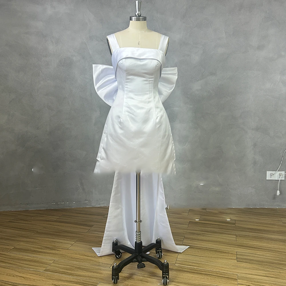 Sleek pure white short satin wedding dress with thick straps, a fitted corset waist, and an attached trailing back overskirt layout on a dress form.