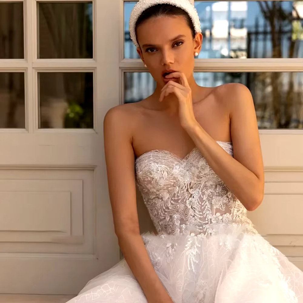 Close-up front view of the model wearing the beaded applique sweetheart wedding dress as a strapless gown silhouette, accessorized with a white pearl-embellished headband.