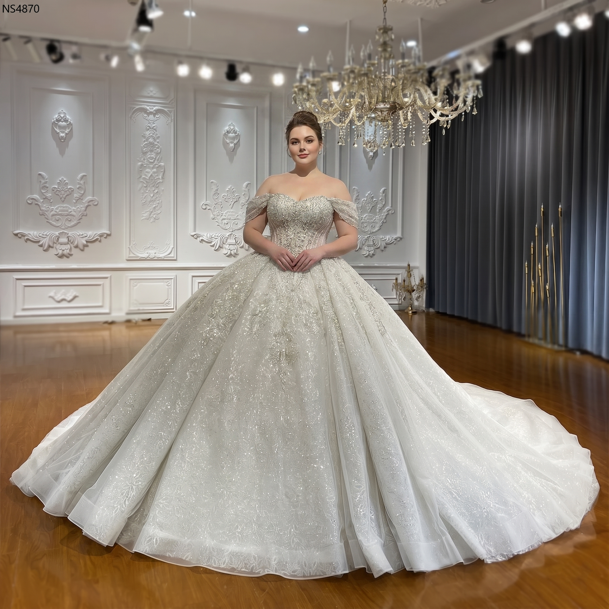 Front perspective of a stunning plus-size bridal gown featuring a voluminous shimmering ball gown skirt and an intricate crystal-embellished sweetheart bodice.
