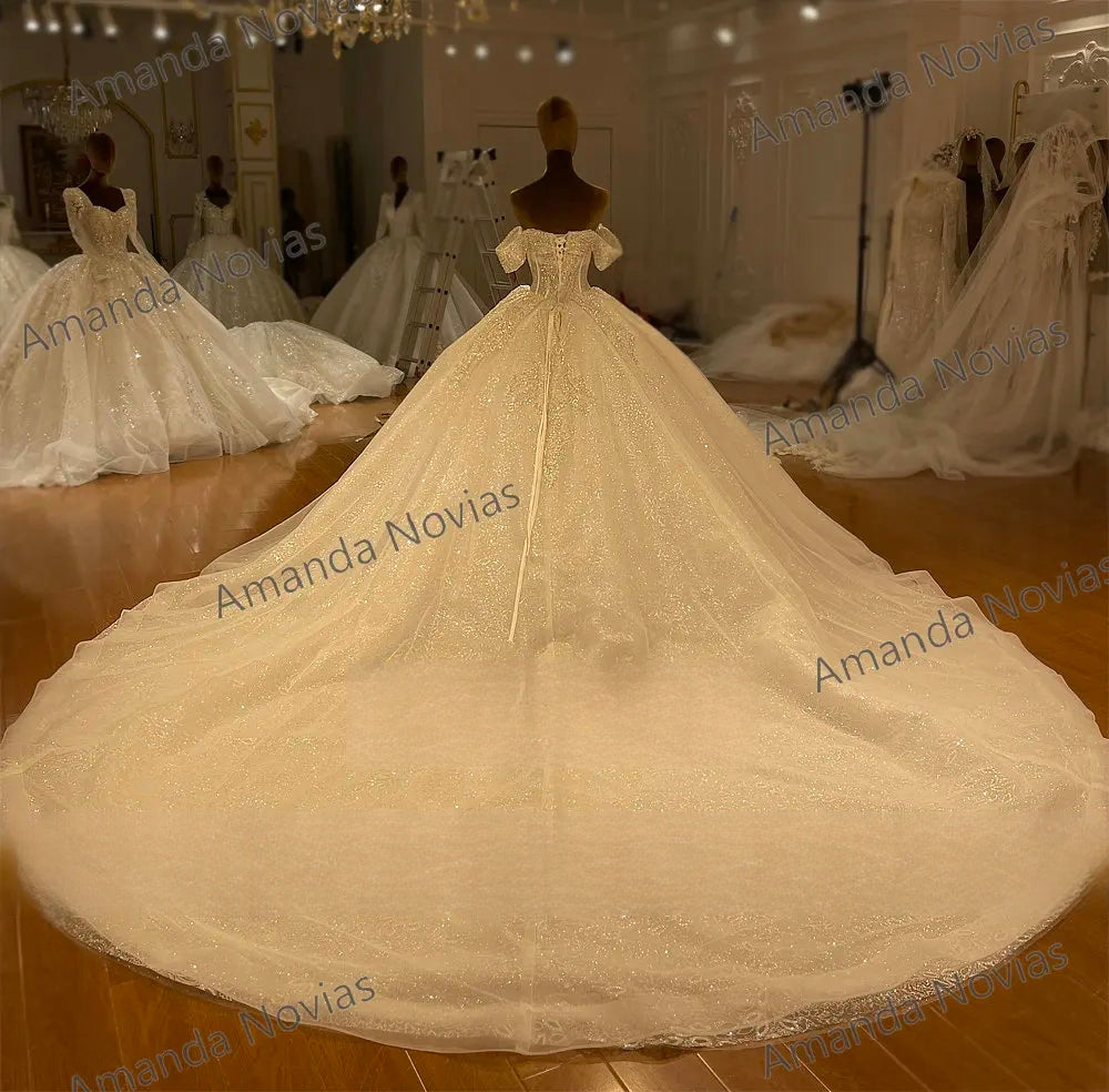 Dramatic rear view of a luxury bridal gown on a mannequin, featuring a sophisticated lace-up corset back and a massive, shimmering long train spread across the floor.