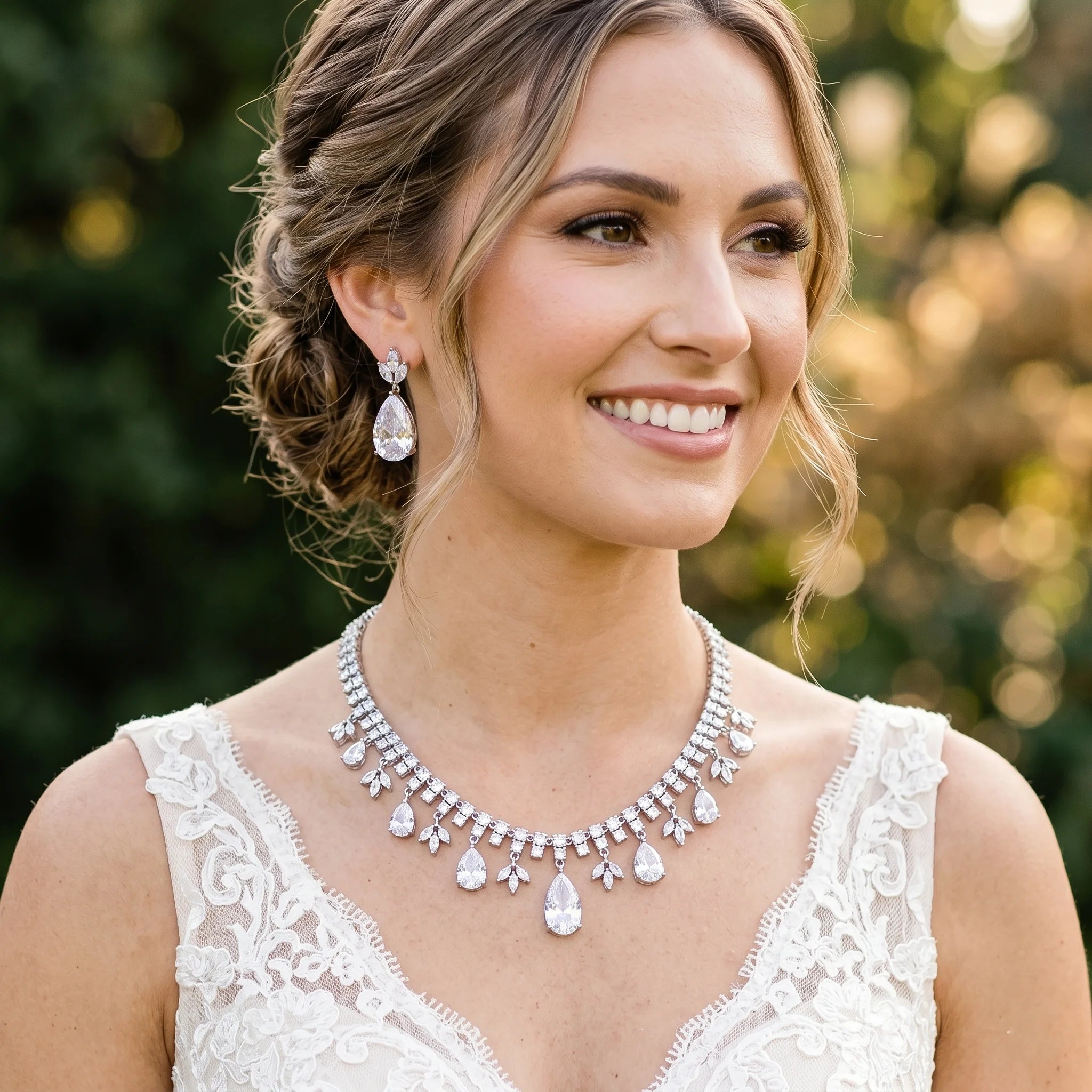 Smiling model wearing a luxury droplet cubic zirconia tassel bridal necklace and matching statement teardrop earrings for a wedding look.