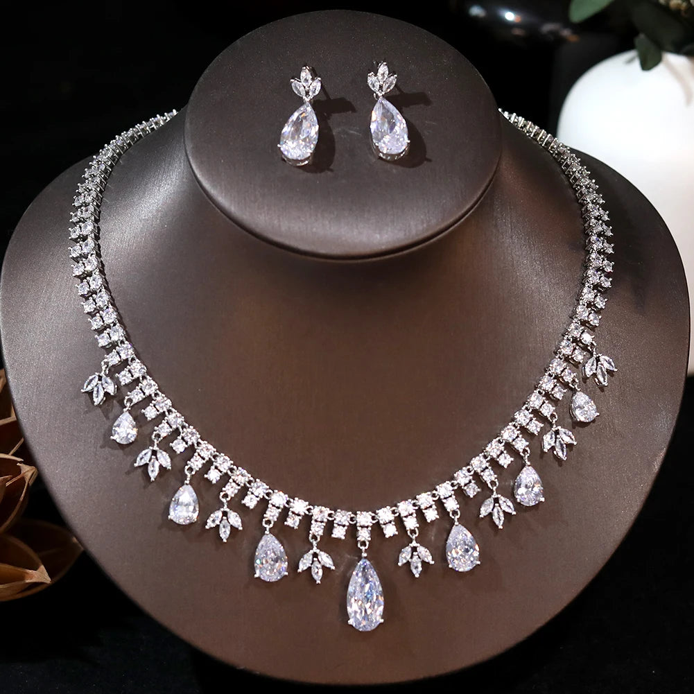 Front profile view of a silver crystal tassel wedding headpiece necklace with teardrop drops and matching earrings on a dark brown jewelry bust.