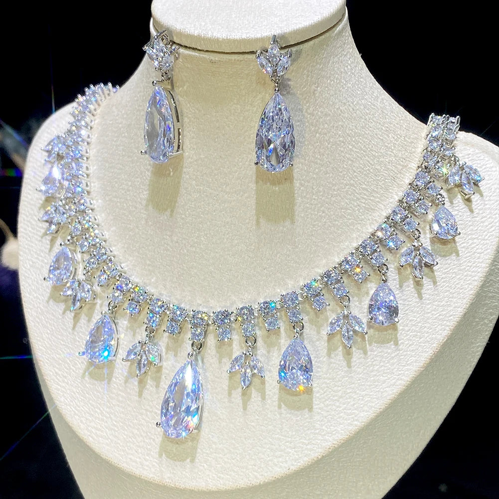 High-angle display of a brilliant cubic zirconia tassel bridal jewelry set showcasing prominent pear-cut teardrop crystals on a cream mannequin.