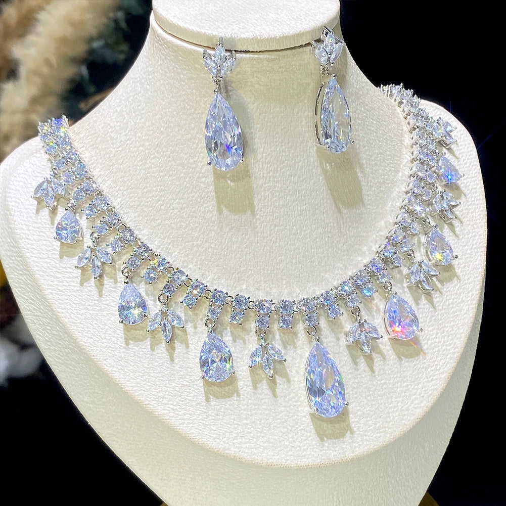 Side-profile perspective of the premium crystal droplet bridal headpiece necklace and dangling teardrop earrings on a textured white display stand.