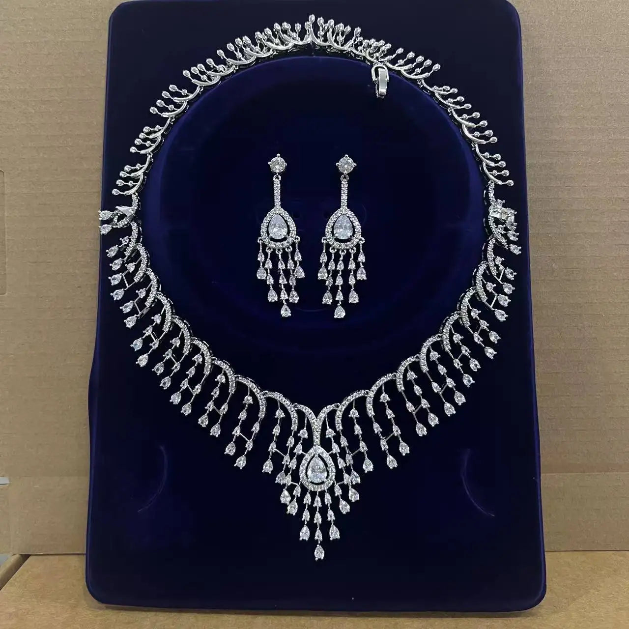 Luxury Dubai white CZ tassel necklace and statement fringe earrings presented inside a dark blue velvet display box.