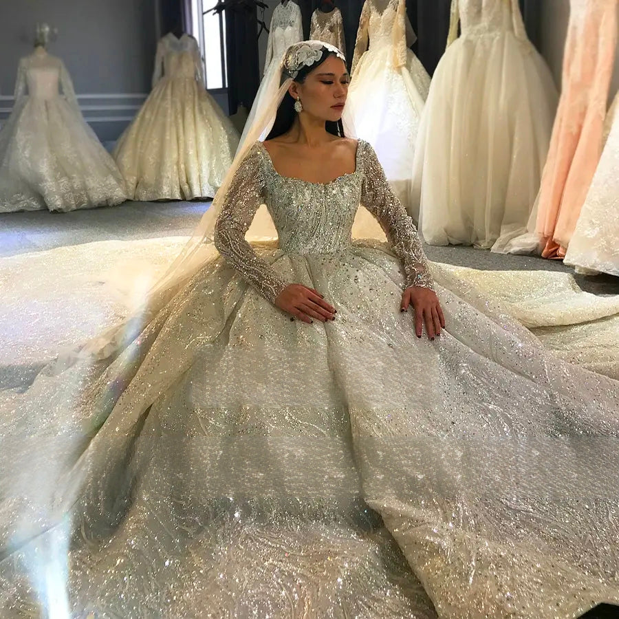 Bride sitting to showcase the expansive sparkling cathedral train and wide-volume skirt of a heavy beaded luxury wedding dress.