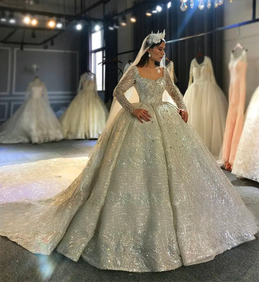 Elegant standing pose highlighting the royal ball gown silhouette and long sparkling train of a Dubai-inspired luxury beaded wedding dress.