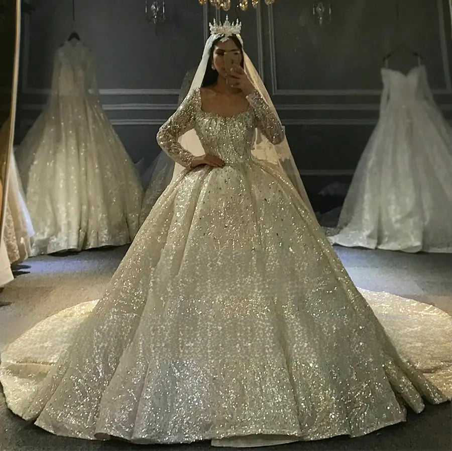 Full-length shimmering silver beaded wedding dress with a grand ball gown skirt and elegant long sleeves, suitable for a royal wedding.
