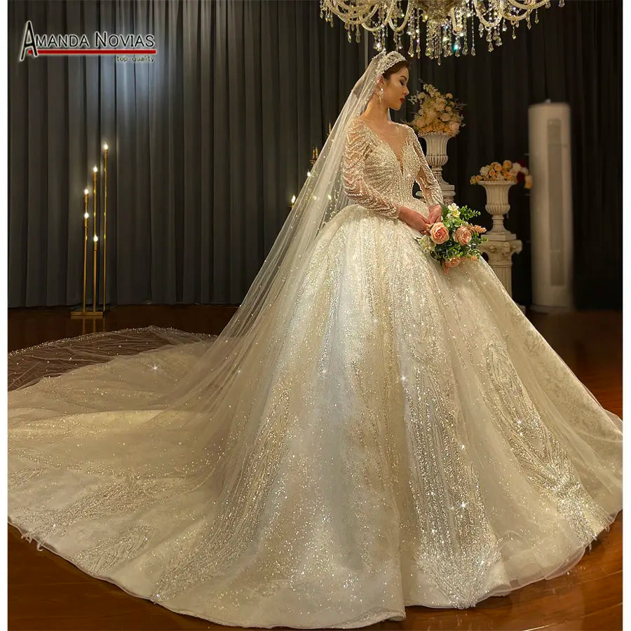Elegant side profile of a champagne royal ball gown wedding dress with a massive sparkling train and long sleeves, showcasing a regal bridal silhouette.